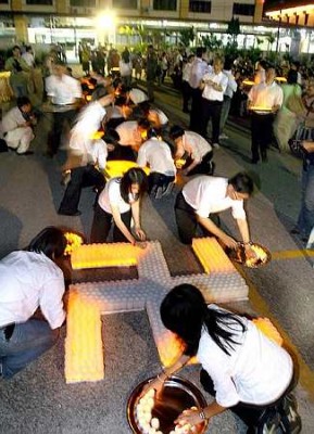 Helping out: Temple helpers arranging the candles to form a Buddhist swastika. image003.jpg